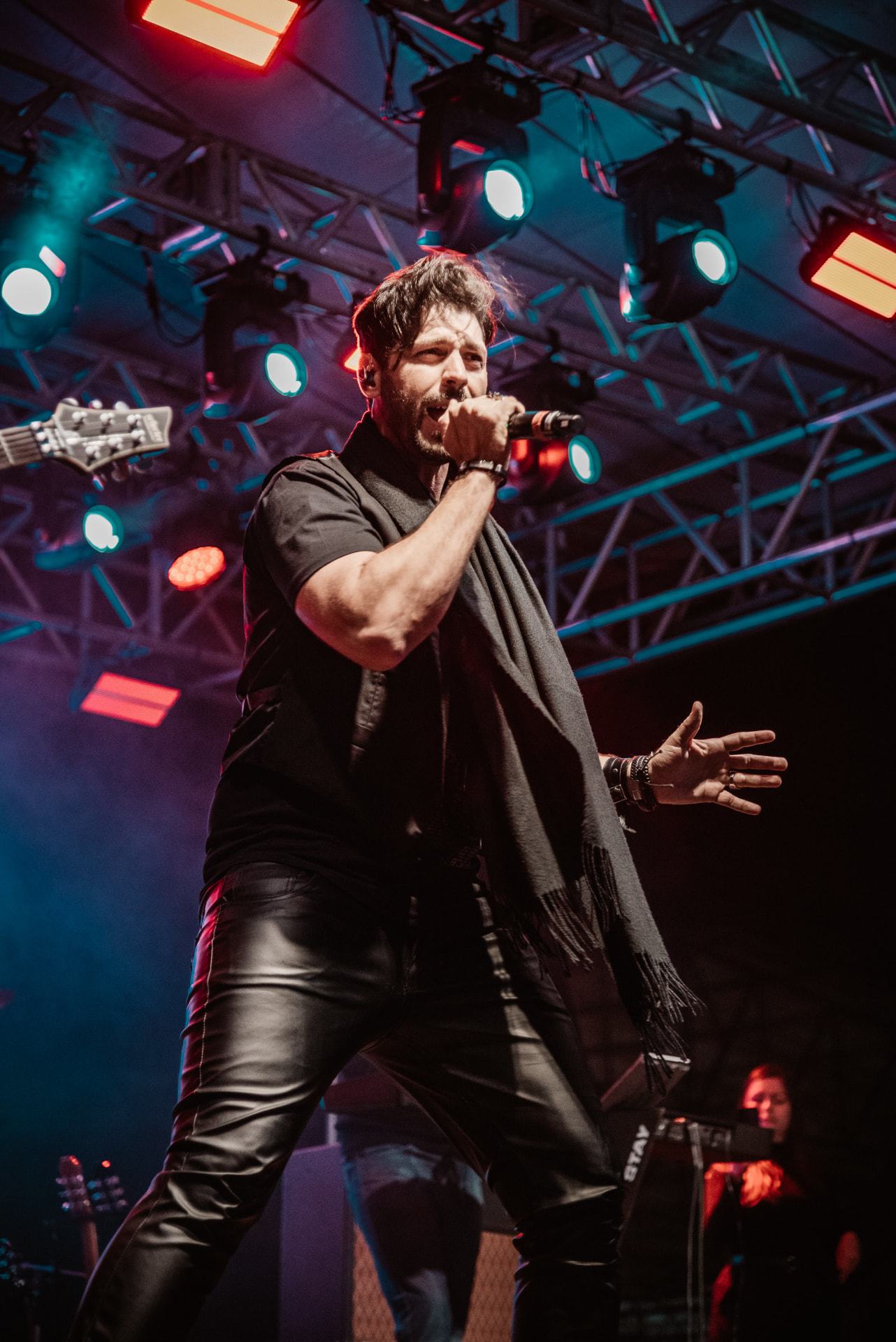 Gui Simões cantando ao vivo com microfone em mãos sob luzes de palco
